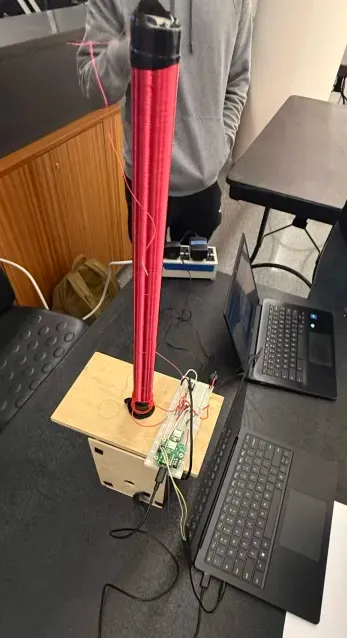 the coil standing upright on its plywood base at projects night, with two laptops beside it