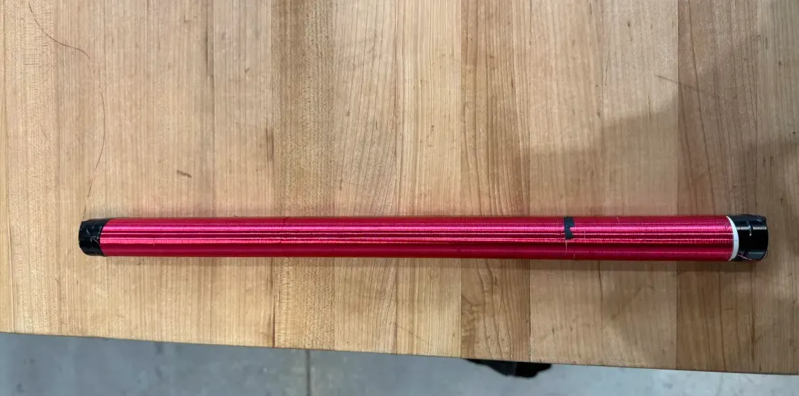 the finished secondary coil, a red copper winding covering a white pvc tube, lying on a workbench
